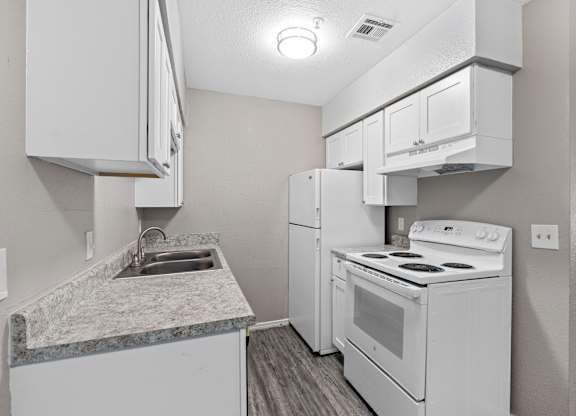 a kitchen with white appliances and white cabinets and a sink at Emerald Greens, Norman, OK 73072