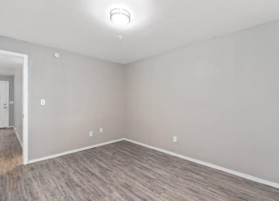 an empty living room with wood flooring and white walls at Emerald Greens, Oklahoma
