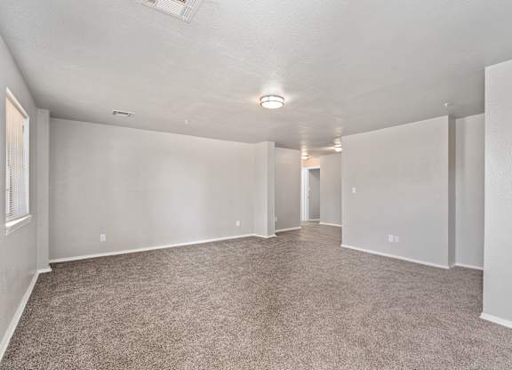 an empty living room with carpet and white walls at Emerald Greens, Norman, 73072
