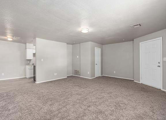 an empty living room with carpet and a white kitchen at Emerald Greens, Oklahoma