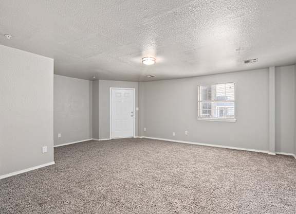 an empty living room with carpet and a white door at Emerald Greens, Norman, OK 73072
