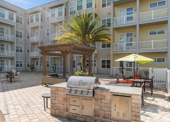 a large outdoor kitchen with a grill in front of an apartment building at Lake Lofts at Deerwood, Jacksonville, FL