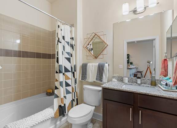a bathroom with a shower toilet and sink and a mirror at Lake Lofts at Deerwood, Jacksonville, FL, 32216