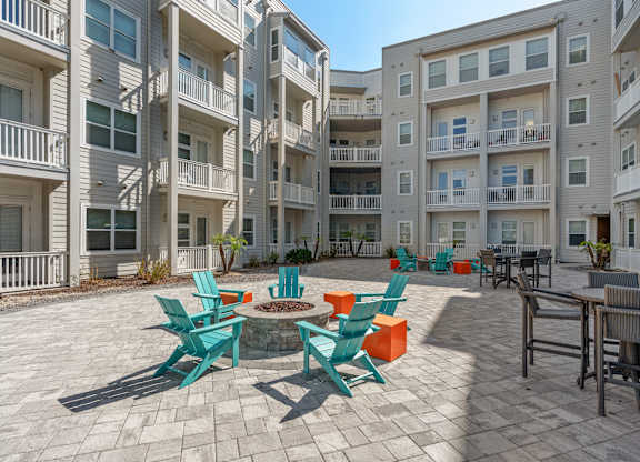 an outdoor patio with chairs and tables in an apartment building at Lake Lofts at Deerwood, Jacksonville, FL, 32216