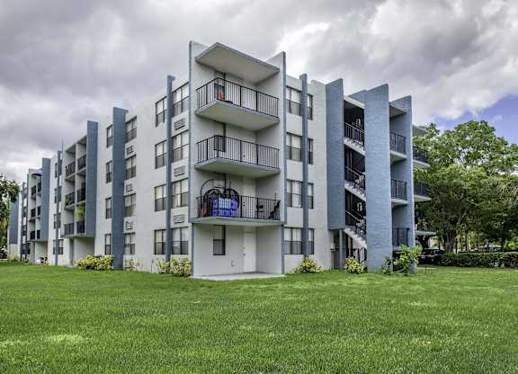 a grey apartment building with a green lawn in front of it  at Club at Emerald Waters, Florida