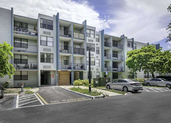 an image of an apartment building with a parking lot in front of it  at Club at Emerald Waters, Hollywood, FL