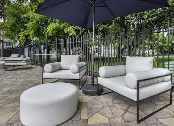 a patio with two white couches and two black umbrellas  at Club at Emerald Waters, Florida