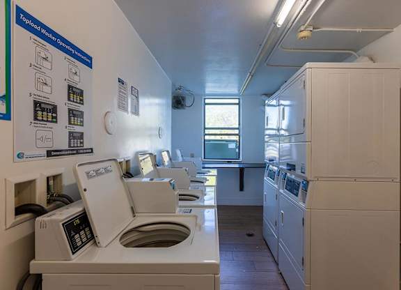 a laundry room with a row of washers and dryers  at Club at Emerald Waters, Hollywood, FL, 33021