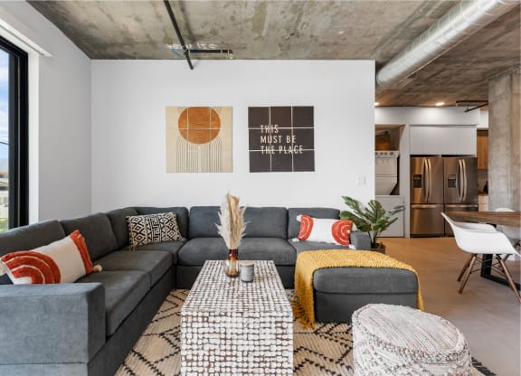 Living room with large sectional, coffee table and sitting pouf.