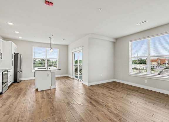 A spacious kitchen and living room with wood flooring and white walls.