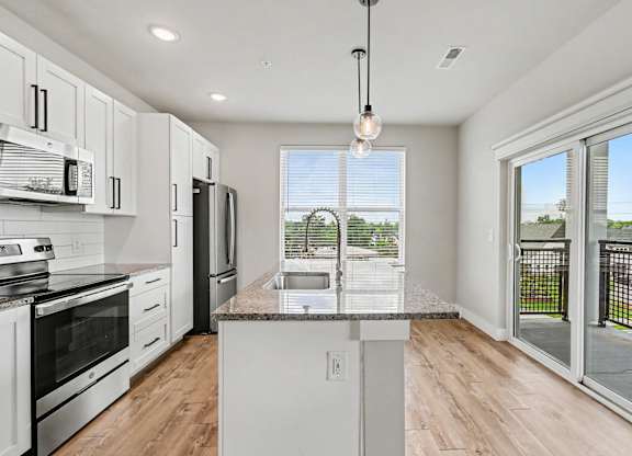 A kitchen with white cabinets and a granite countertop.