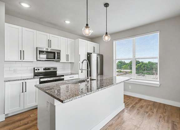 A kitchen with granite countertops and white cabinets.