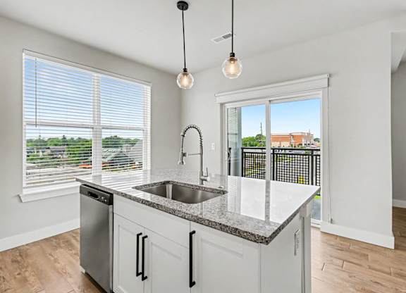 A kitchen with a dishwasher, sink, and window.