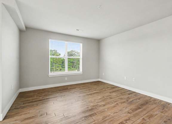 Empty room with wooden flooring and a window.