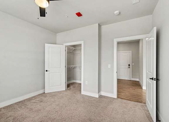 A room with a carpeted floor and a ceiling fan with a light.