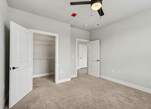 A room with white doors and carpeted floor.