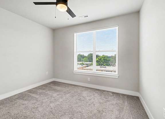 A room with a ceiling fan and a window with blinds.