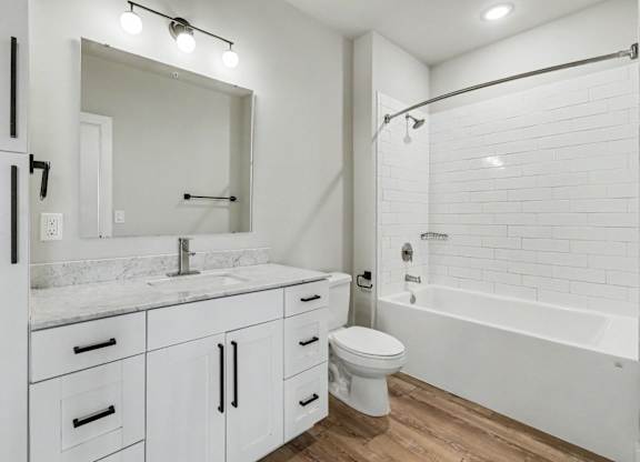 A white bathroom with a sink, mirror, toilet, and bathtub.