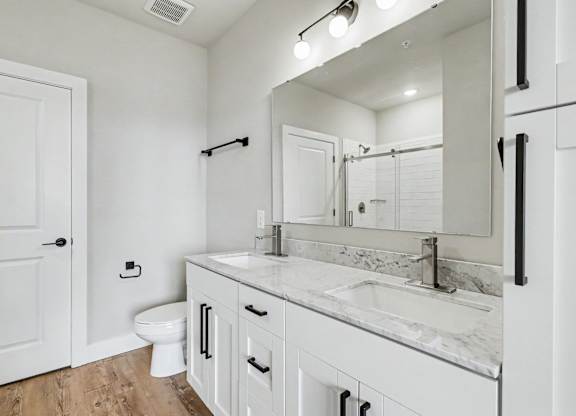 A white bathroom with a toilet, sink, and mirror.