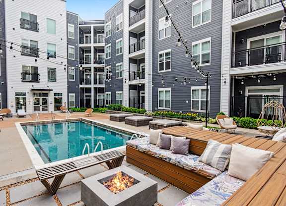 A modern apartment complex with a pool and outdoor seating area.