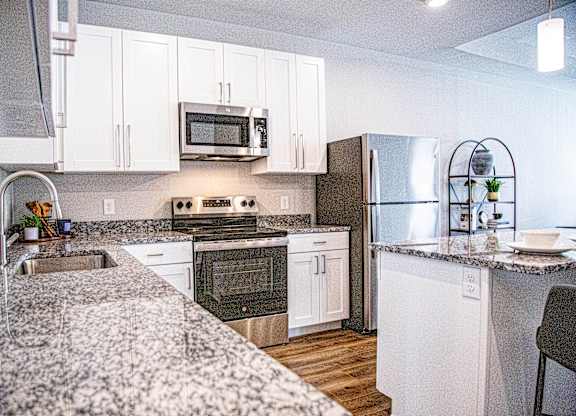 A modern kitchen with granite countertops and stainless steel appliances at French District Villas Apartments, St. Charles