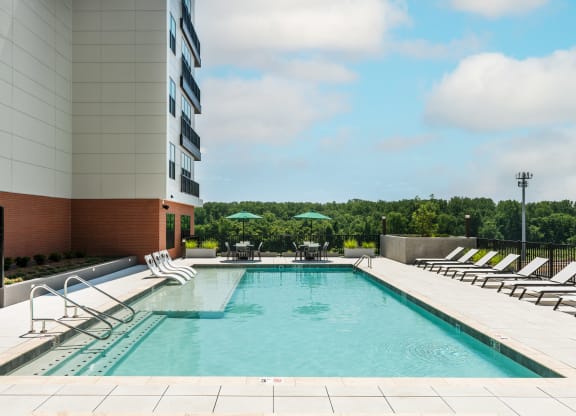 Sparkling swimming pool with sun tanning ledge, lounge chairs and two covered bistro tables  at Chapter at the Streets of St Charles, Missouri, 63303