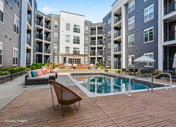A chair is on a wooden deck next to a pool.