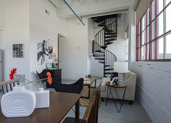 Steelcote Lofts dining/living room area with polished concrete floors, white exposed brick walls and black spiral staircase at Steelcote Square, St. Louis, MO
