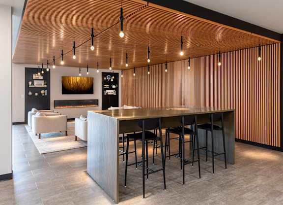 A modern bar with a wooden ceiling and a long counter.