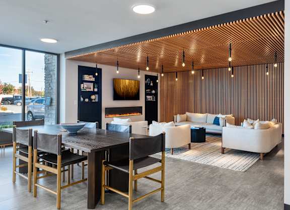 A modern living room with a dark wood dining table and white couches.