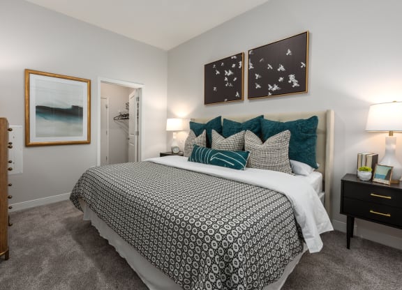 Modern bedroom with large bed, night stand, dresser and door leading to walk-in closet  at Chapter at the Streets of St Charles, Saint Charles, MO, 63303