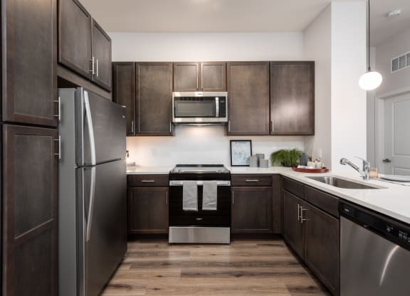 Modern kitchen with designer lighting, dark cabinetry and stainless steel appliances  at Chapter at the Streets of St Charles, Saint Charles, MO