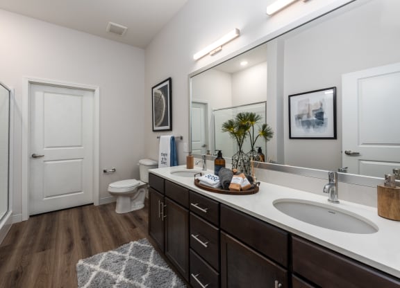 Modern bathroom with double vanity with granite countertops, dark cabinetry, designer lighting and walk in shower  at Chapter at the Streets of St Charles, Saint Charles, MO