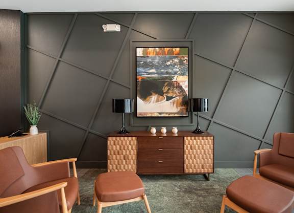 A room with a brown chair, a brown cabinet, and a painting on the wall at The Oliver Apartments, Missouri