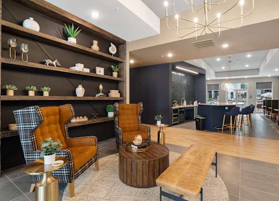 A modern living room with a wooden floor and a variety of seating options at The Oliver Apartments, Olivette, 63132