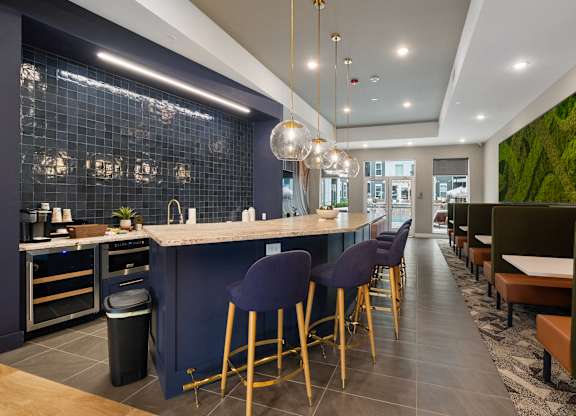 A modern kitchen with a bar area and a green wall at The Oliver Apartments, Olivette, 63132