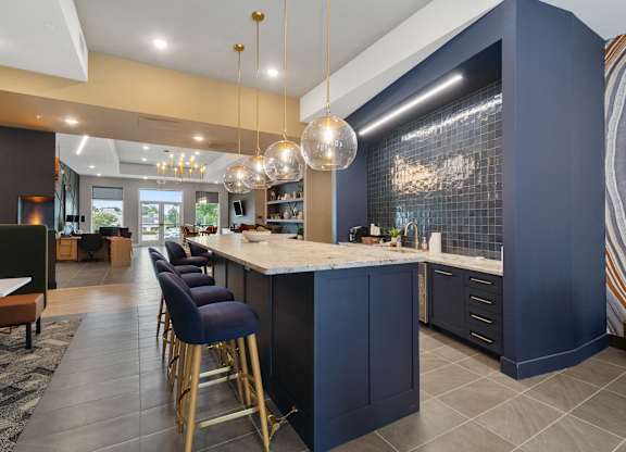 A kitchen with dark blue cabinets and a bar area with stools at The Oliver Apartments, Olivette, Missouri