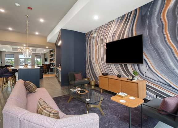 A modern living room with a flat screen TV and a large couch at The Oliver Apartments, Olivette, MO