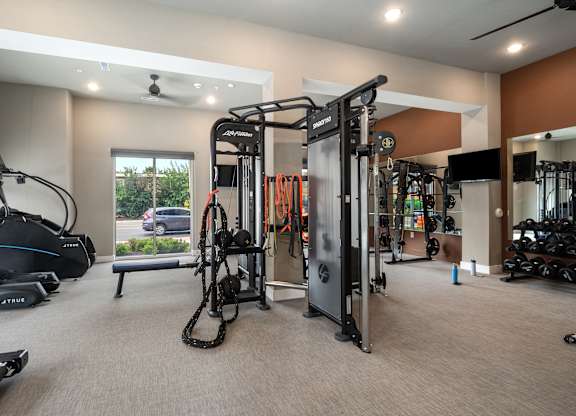 A gym with a variety of equipment including treadmills, weights, and a bench at The Oliver Apartments, Missouri, 63132