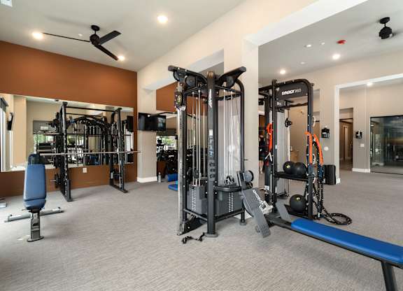 A gym with a variety of equipment including a bench, weights, and a treadmill at The Oliver Apartments, Olivette, MO