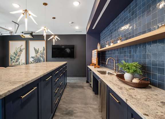 A kitchen with dark blue cabinets and a marble countertop at The Oliver Apartments, Olivette, Missouri