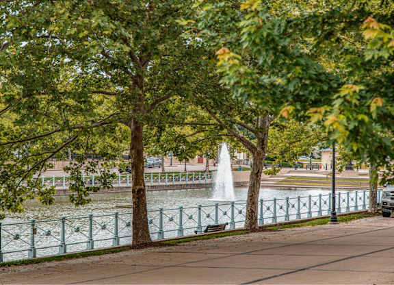 A fountain is in the middle of a lake surrounded by trees at French District Villas Apartments, St. Charles, MO 63301