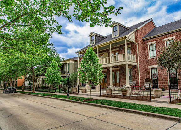 A red brick house with a balcony and a tree in front at French District Villas Apartments, Missouri 63301