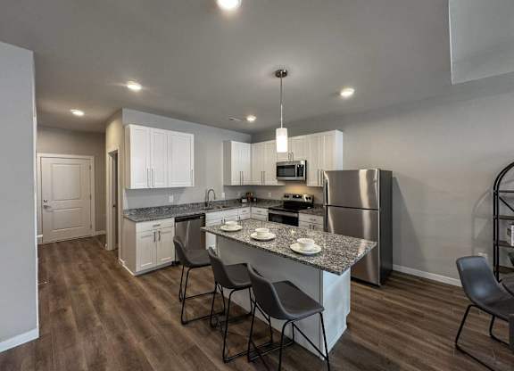 A kitchen with a granite countertop and stainless steel appliances at French District Villas Apartments, Missouri 63301