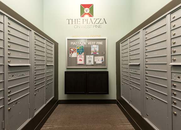 A hallway with lockers and a sign that says The Piazza on West Pine.