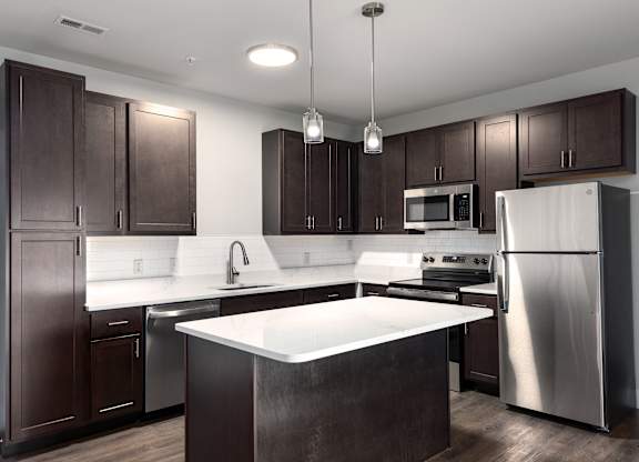 A modern kitchen with dark brown cabinets and stainless steel appliances.