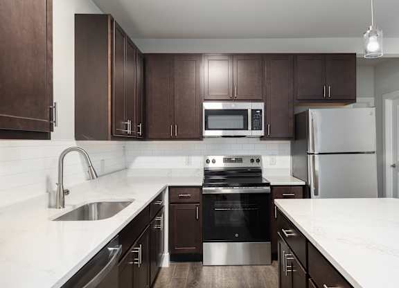 A modern kitchen with dark brown cabinets and stainless steel appliances.