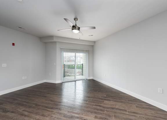 A room with a ceiling fan and sliding glass doors.