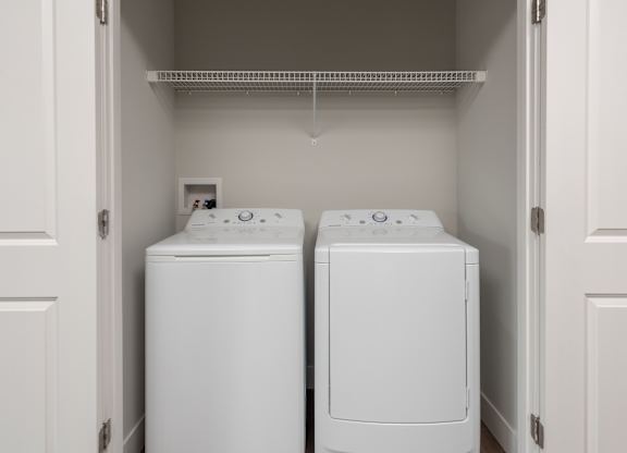 Two white front load washing machines in a laundry room.