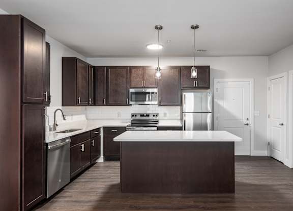 A modern kitchen with dark brown cabinets and a white countertop.